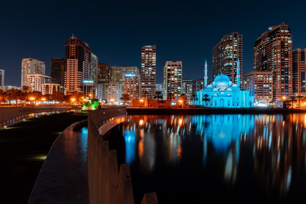 Mosque in warm gold reflected in the lagoon with skyline