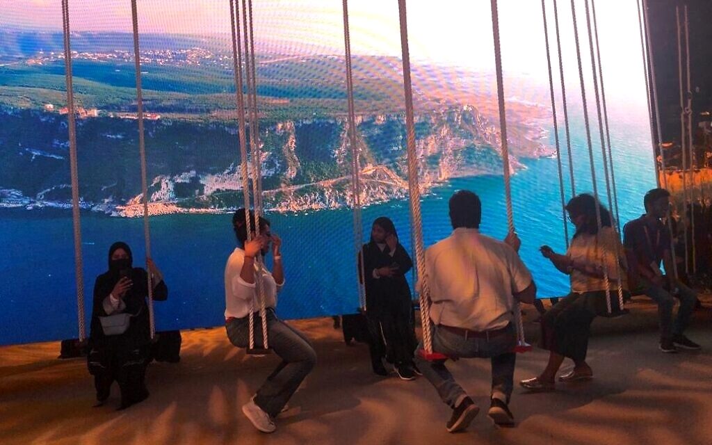 Visitors swinging under aerial Lebanon coastline projection